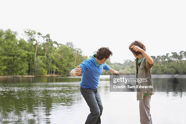 padre e hijo rebotar piedras en el agua en el lago - dar brincos fotografías e imágenes de stock