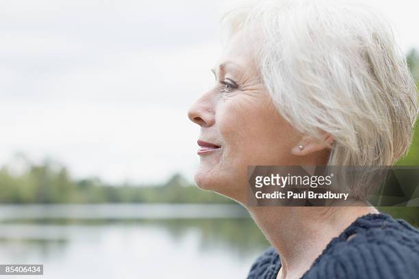 mujer senior cerca de lake - gray hair fotografías e imágenes de stock