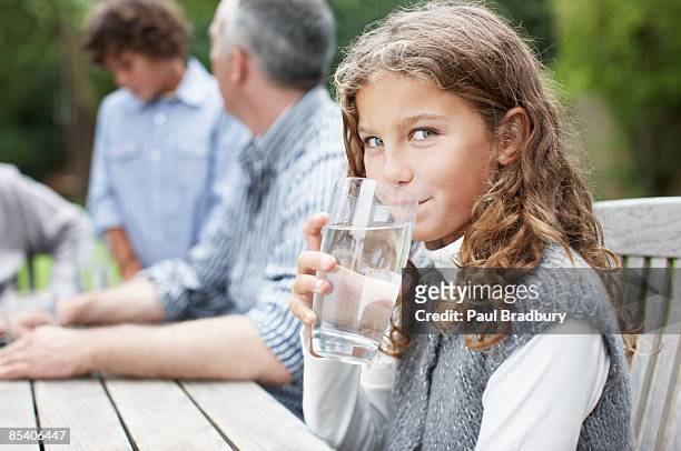 mädchen trinkwasser beim picknick-tisch - wasserglas stock-fotos und bilder