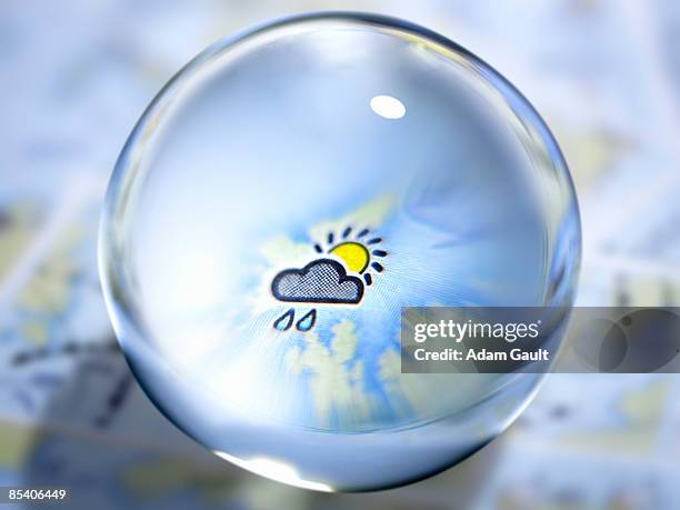 close up of glass ball with rain cloud and sun in center - world weather map photos et images de collection