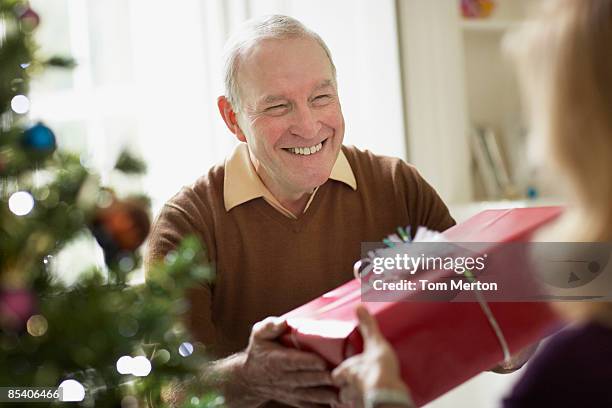 senior man giving wife christmas gift - exchanging gifts stock pictures, royalty-free photos & images