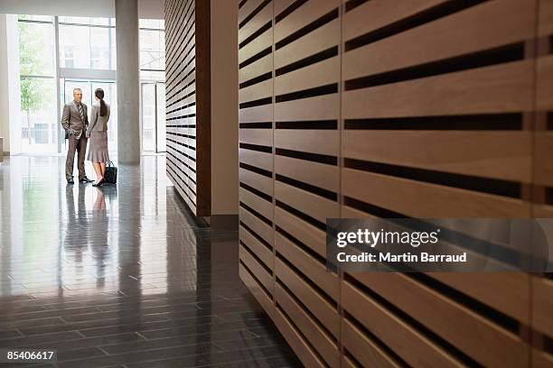 businesspeople talking in corridor - business introduction stock pictures, royalty-free photos & images