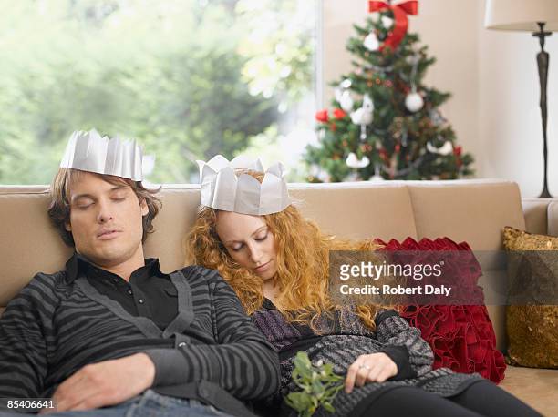 sleeping couple wearing paper crowns at christmas - paper crown stock pictures, royalty-free photos & images