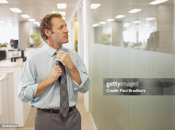 businessman adjusting tie in office - arrogance 個照片及圖片檔