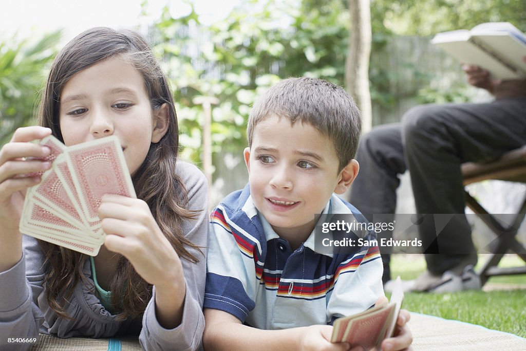 Brother and sister playing cards outdoors