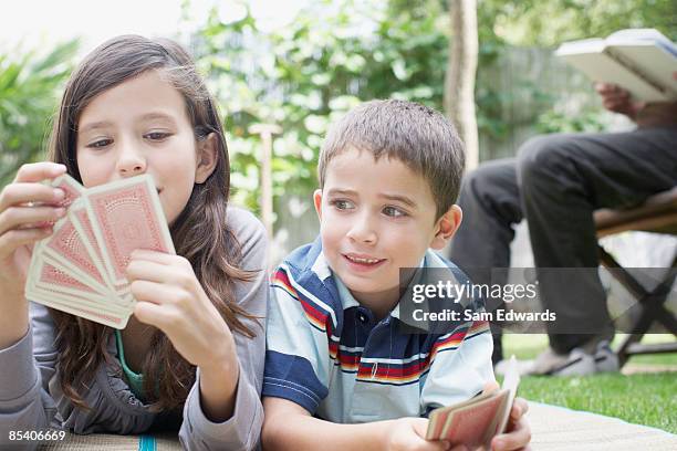 brother and sister playing cards outdoors - liar stock pictures, royalty-free photos & images