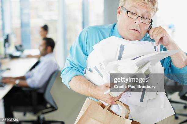 businessman talking on phone holding paperwork and coffee - overworked stock pictures, royalty-free photos & images