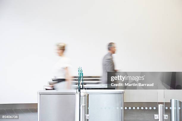 businesspeople walking through turnstile - office motion stock pictures, royalty-free photos & images