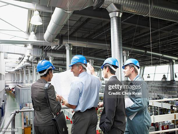 businesspeople in hard-hats looking at blueprints - architekt helm plan stock pictures, royalty-free photos & images