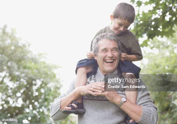 grandfather carrying grandson on shoulders - man touching shoulder stockfoto's en -beelden