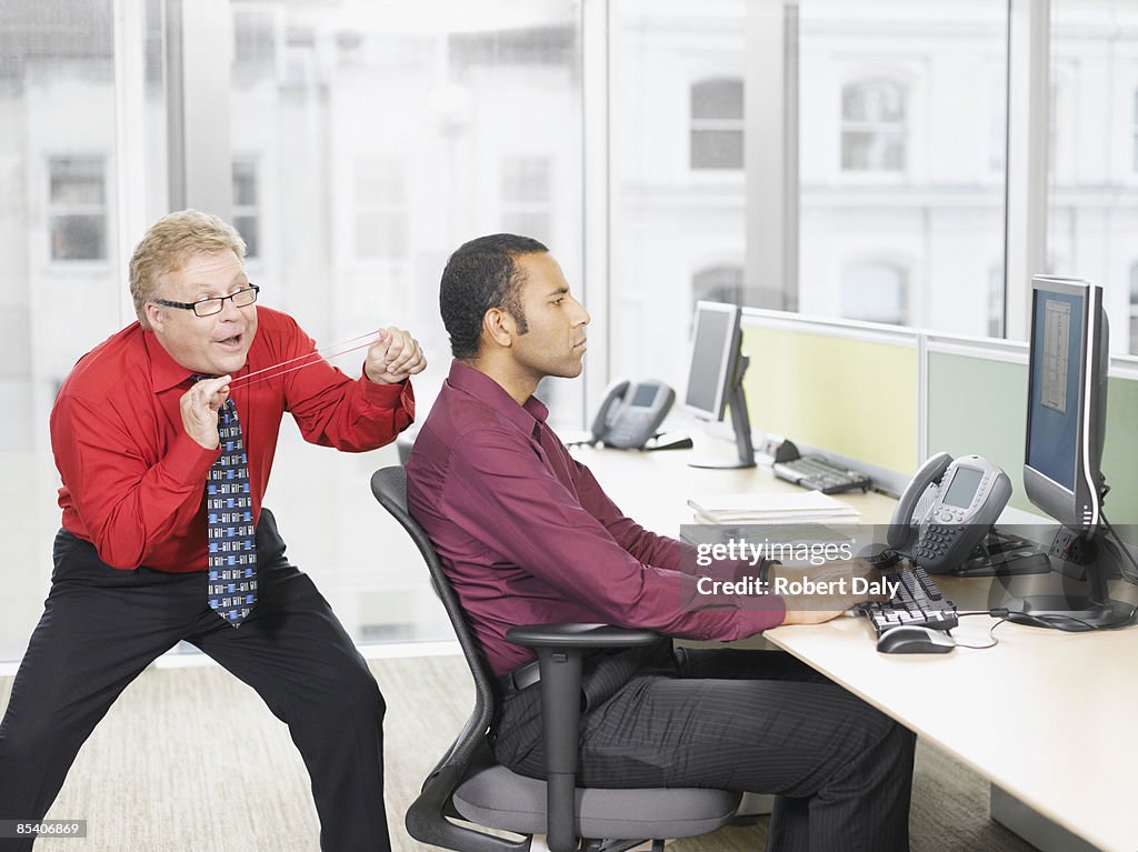 Businessman hitting co-worker with rubber band