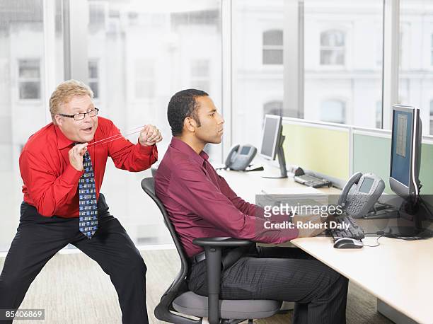 businessman hitting co-worker with rubber band - taunts stock pictures, royalty-free photos & images