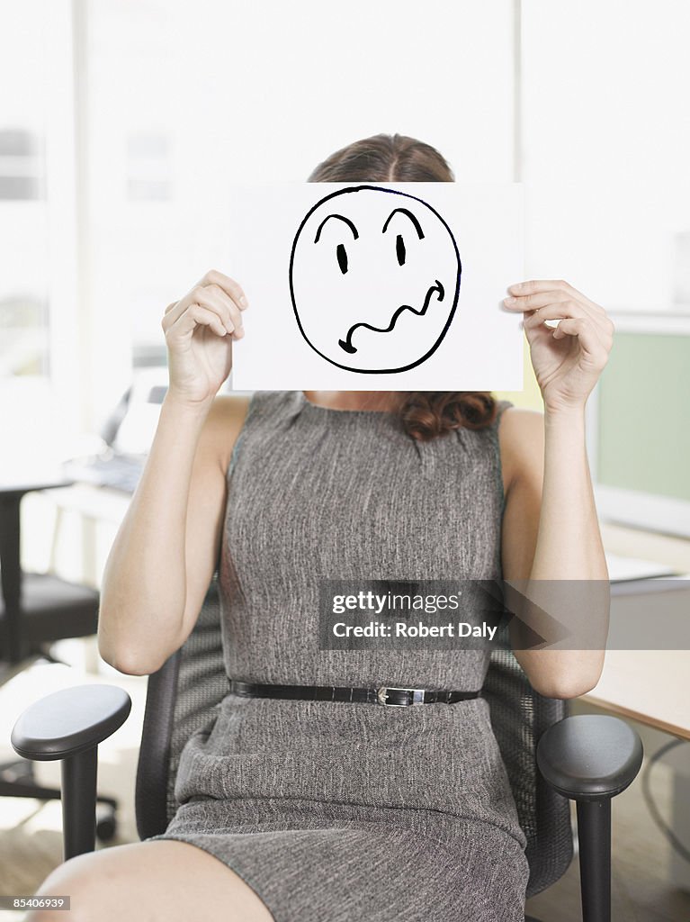 Businesswoman holding picture of frustrated face