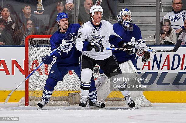 Ian White of the Toronto Maple Leafs battles with Ryan Malone of the Tampa Bay Lightning in front of goalie Martin Gerber during game action March...