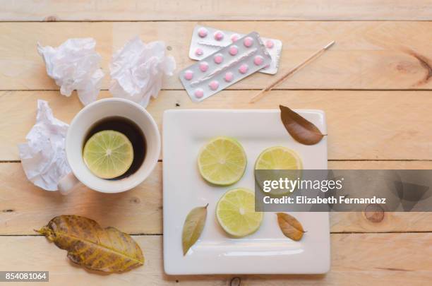 cold and flu concept. cup of tea, lemon slices, thermometer, tissues and pills. - lemon on an injury stock pictures, royalty-free photos & images