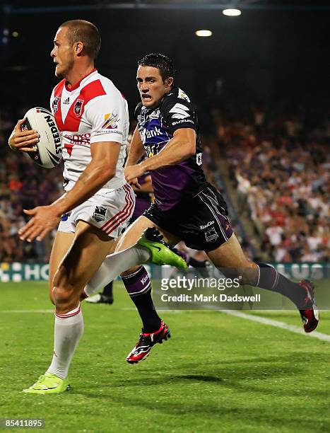 Matt Cooper of the Dragons races away from Cooper Cronk of the Storm on his way to scoring a try during the round one NRL match between the Melbourne...