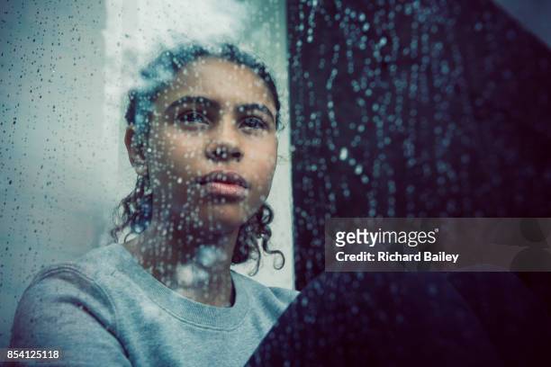 girl staring out of rainy window - sadness stock-fotos und bilder