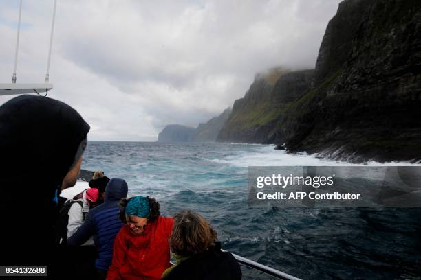 This Picture taken on September 11 shows tourists sailing with a boat near Vastmaana, in one of the 18 Faroe Islands located between the North...