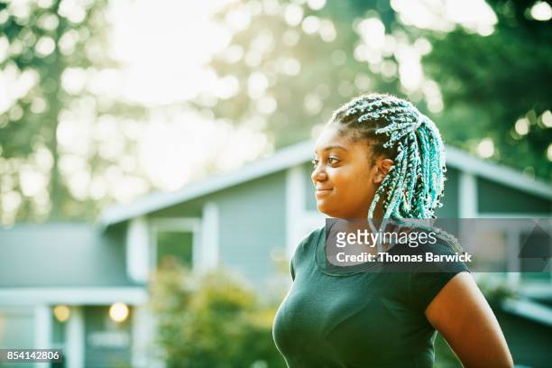 Portrait of smiling young woman standing in front yard on summer evening