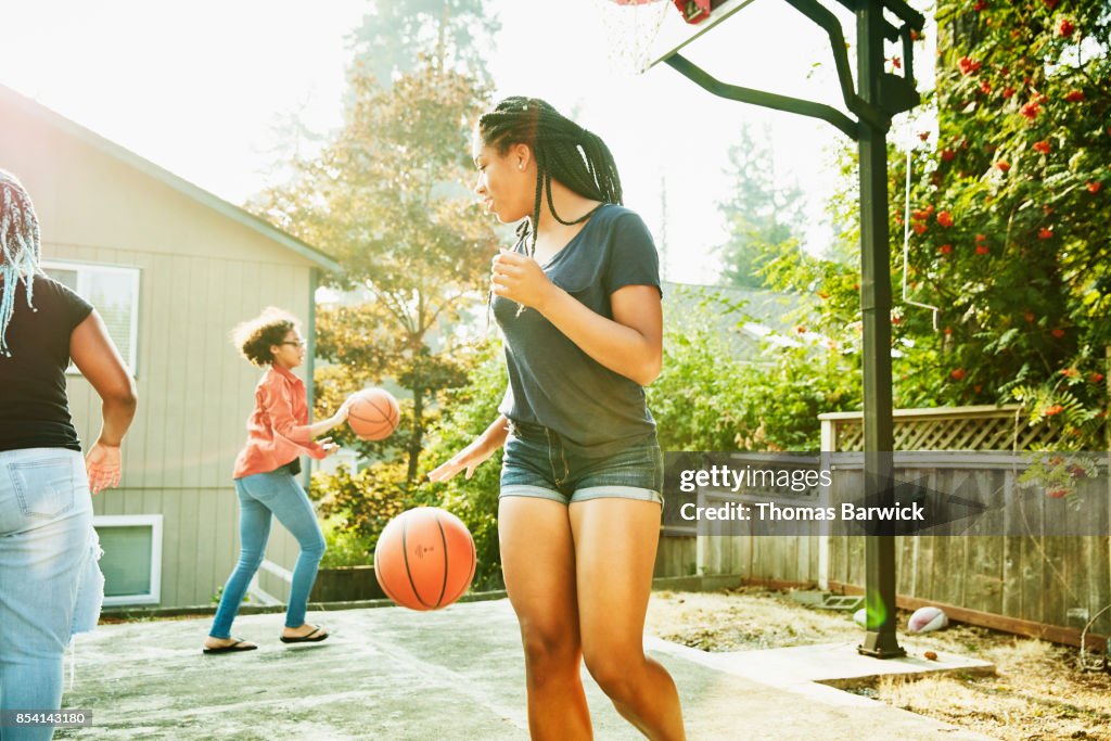 Young women playing basketball in backyard on summer afternoon