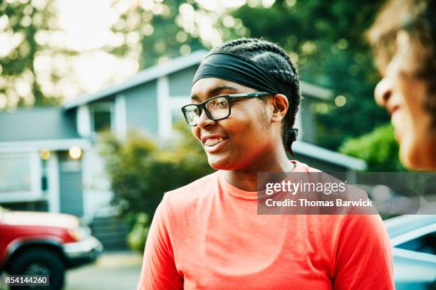 Smiling young woman hanging out with neighborhood friends on summer evening