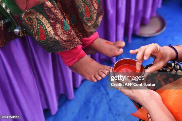 Local Bhartiya Janta Party leader prepares to touch the feet of the daughter of a labourer during the 'Kanya Poojan' ritual of the ongoing 'Navratri'...