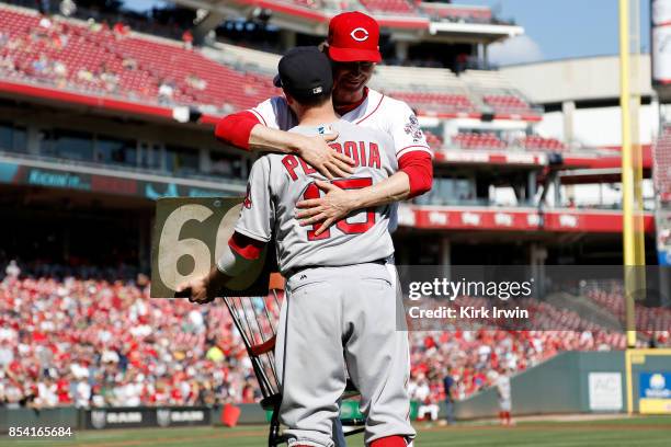 Bronson Arroyo of the Cincinnati Reds hugs Dustin Pedroia of the Boston Red Sox after he presents him with the number 61 from the scoreboard at...