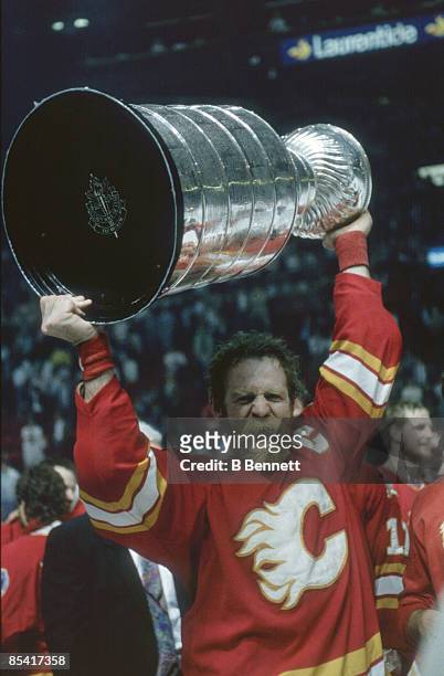Canadian ice hockey player Lanny McDonald of the Calgary Flames yells triumphantly as he holds the Stanley Cup trophy aloft after his team's victory...