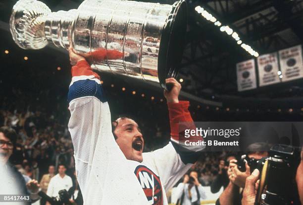 Canadian ice hockey player Bryan Trottier of the New York Islanders shouts triumphanly as he holds aloft the Stanley Cup in celebration of his team's...