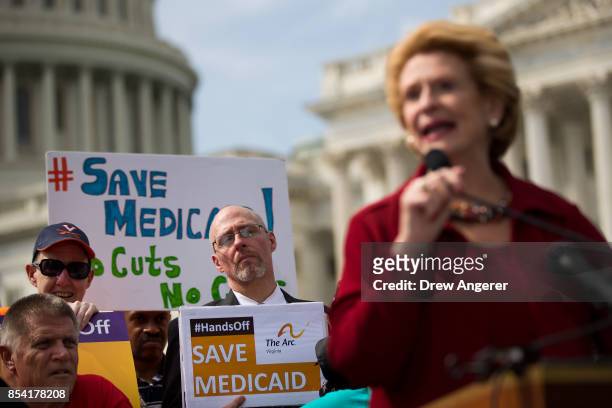 Health care activists look on as Sen. Debbie Stabenow speaks during a news conference in opposition to the Graham-Cassidy health care bill, September...