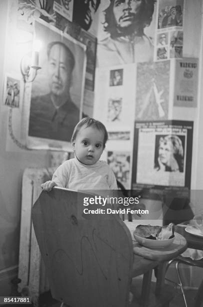 An unidentified infant stand in a highchair in a room whose walls are cover with leftist posters, including images of Mao and Che Guevara, Ann Arbor,...