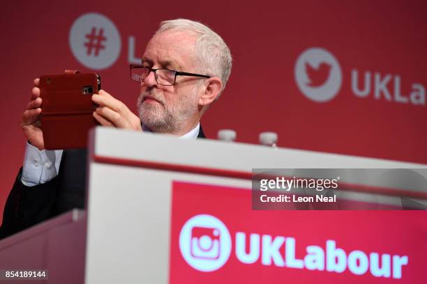 Labour party leader Jeremy Corbyn takes a picture on his mobile phone as Deputy Labour party leader Tom Watson speaks to delegates in the main hall,...