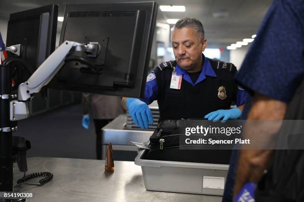 Transportation Security Administration worker screens luggage at LaGuardia Airport on September 26, 2017 in New York City. Passengers traveling on...