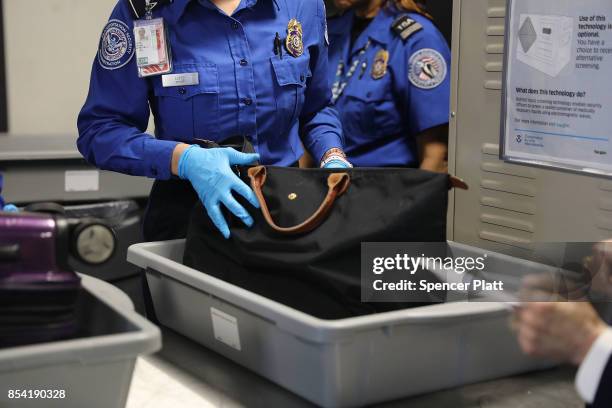 Transportation Security Administration worker screens luggage at LaGuardia Airport on September 26, 2017 in New York City. Passengers traveling on...