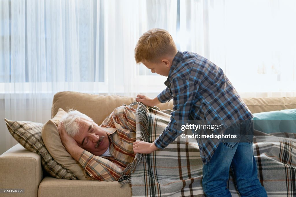 Attento nipote che copre il nonno con coperta