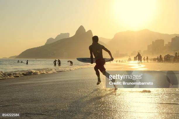 surfer, die zum meer laufen - ipanema beach stock-fotos und bilder