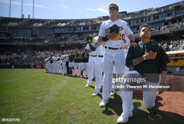 Bruce Maxwell of the Oakland Athletics kneels in protest next to teammate Mark Canha duing the singing of the National Anthem prior to the start of...