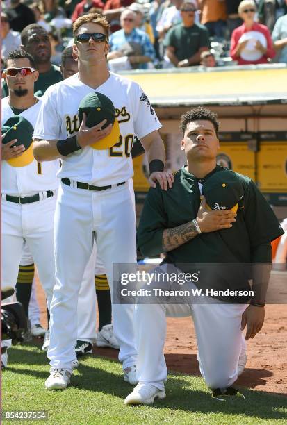 Bruce Maxwell of the Oakland Athletics kneels in protest next to teammate Mark Canha duing the singing of the National Anthem prior to the start of...