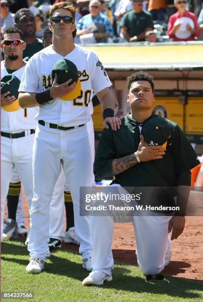 Bruce Maxwell of the Oakland Athletics kneels in protest next to teammate Mark Canha duing the singing of the National Anthem prior to the start of...