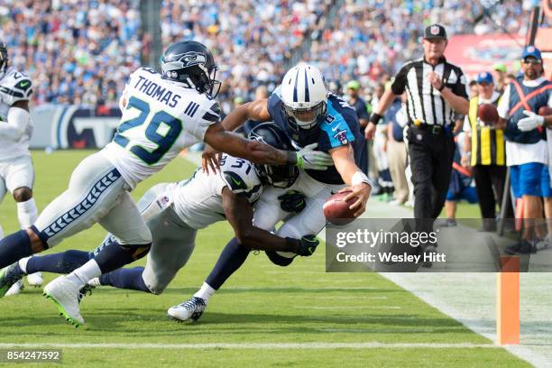 Marcus Mariota of the Tennessee Titans reaches out the ball for a touchdown that is called back on a penalty and is tackled by Kam Chancellor and...