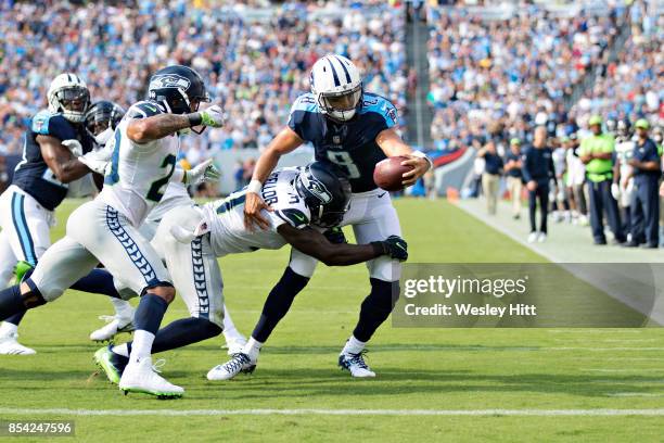 Marcus Mariota of the Tennessee Titans runs the ball and is tackled by Kam Chancellor and Earl Thomas of the Seattle Seahawks at Nissan Stadium on...