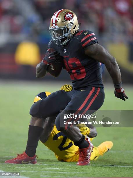 Carlos Hyde of the San Francisco 49ers carries the ball and looks to break the tackle of Mark Barron of the Los Angeles Rams during their NFL...