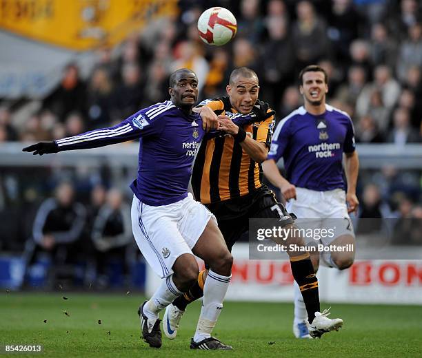 Sebastien Bassong of Newcastle United and Craig Fagan of Hull City battle for the ball during the Barclays Premier League match between Hull City and...