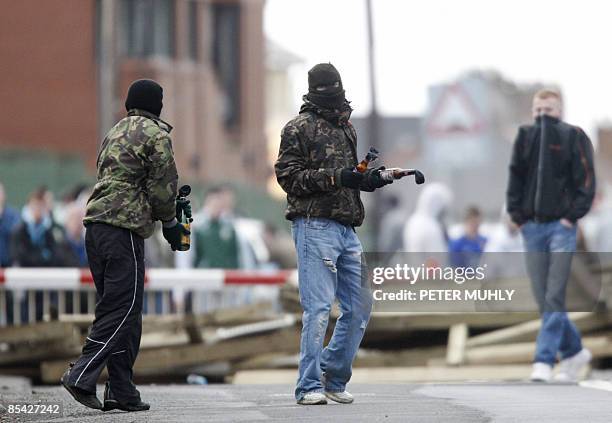 Masked youths prepare to throw molotov cocktails as they block the railway line near the house of former Irish Republican Army man Colin Duffy in...