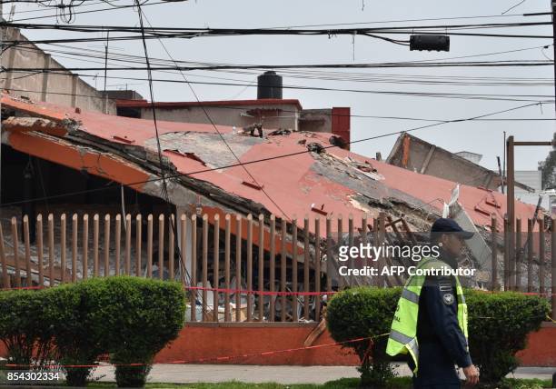 Police officer patrolling a street closed to traffic passes by a building knocked down by the 7.1-magnitude earthquake one week ago in Xochimilco,...