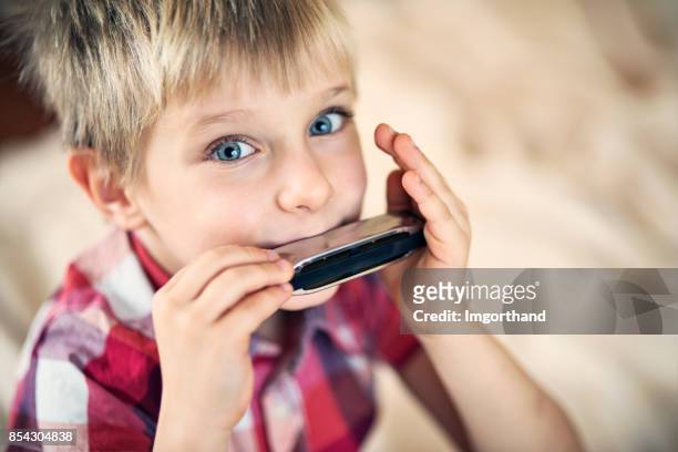 cute little boy playing harmonica - harmonica stock pictures, royalty-free photos & images