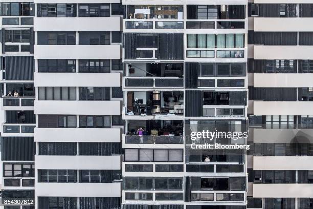 Residents stand on balconies in a building damaged from Hurricane Maria in the Ocean Park neighborhood of San Juan, Puerto Rico, on Monday, Sept. 25,...