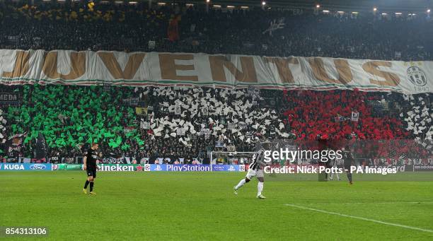 Juventus fans hold a giant banner and flags bearing the colours of the Italian national flag in the stands