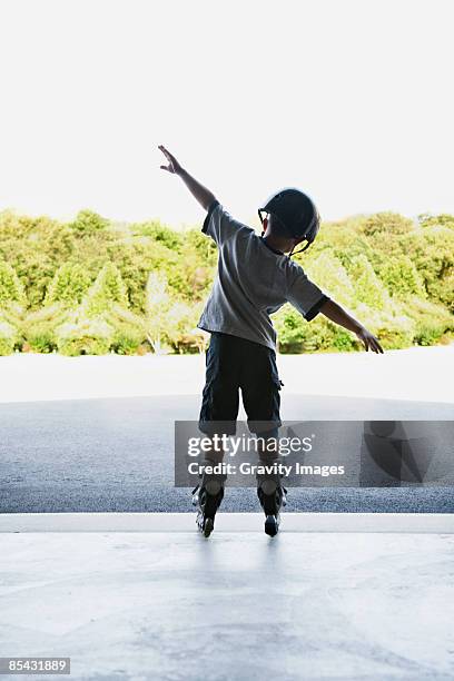 young boy standing with arms out on roller blades - 飛行機のまね ストックフォトと画像