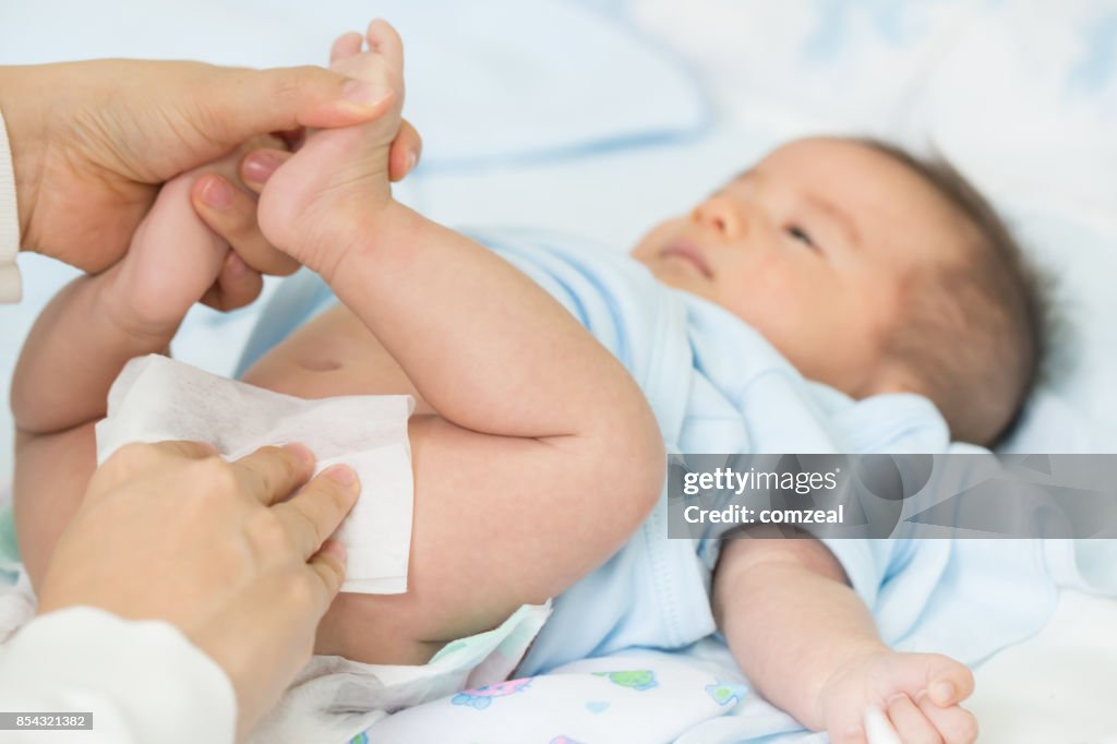 Mother cleaning up and wipes the baby buttocks by wet tissue